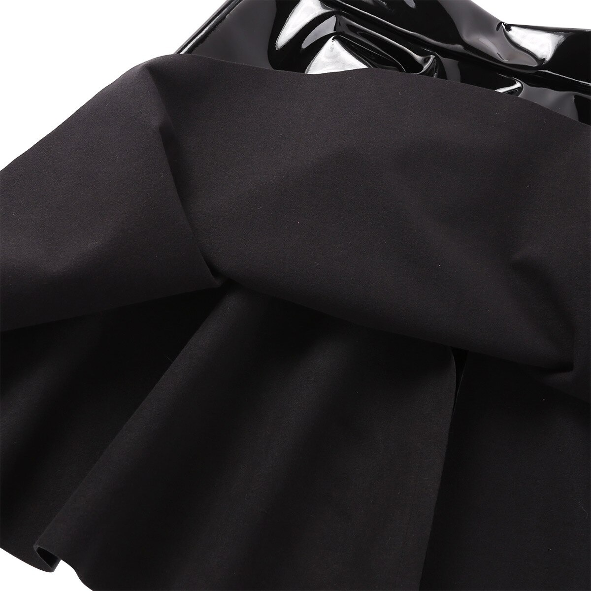 Close-up of a black PU leather flared mini skirt showing pleats and texture, perfect for trendy casual styling.