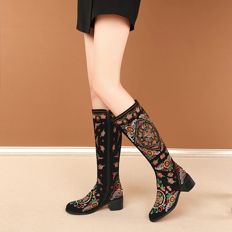 Women's knee high embroidered boots in black suede with stylish thick heels and a vibrant ethnic design.