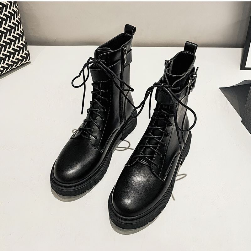 Stylish women's black lace-up ankle motorcycle boots with buckle and platform sole on a modern surface.