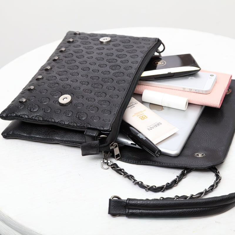 Women's leather gothic handbag showcasing a zippered black bag filled with stylish accessories and smartphones.