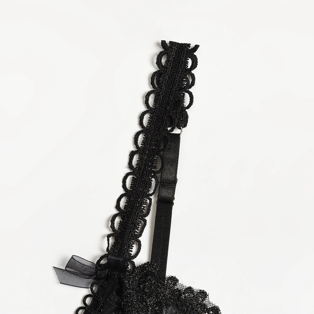 Close-up of a black lace bra strap featuring decorative scalloped detailing, ideal for gothic lingerie style.