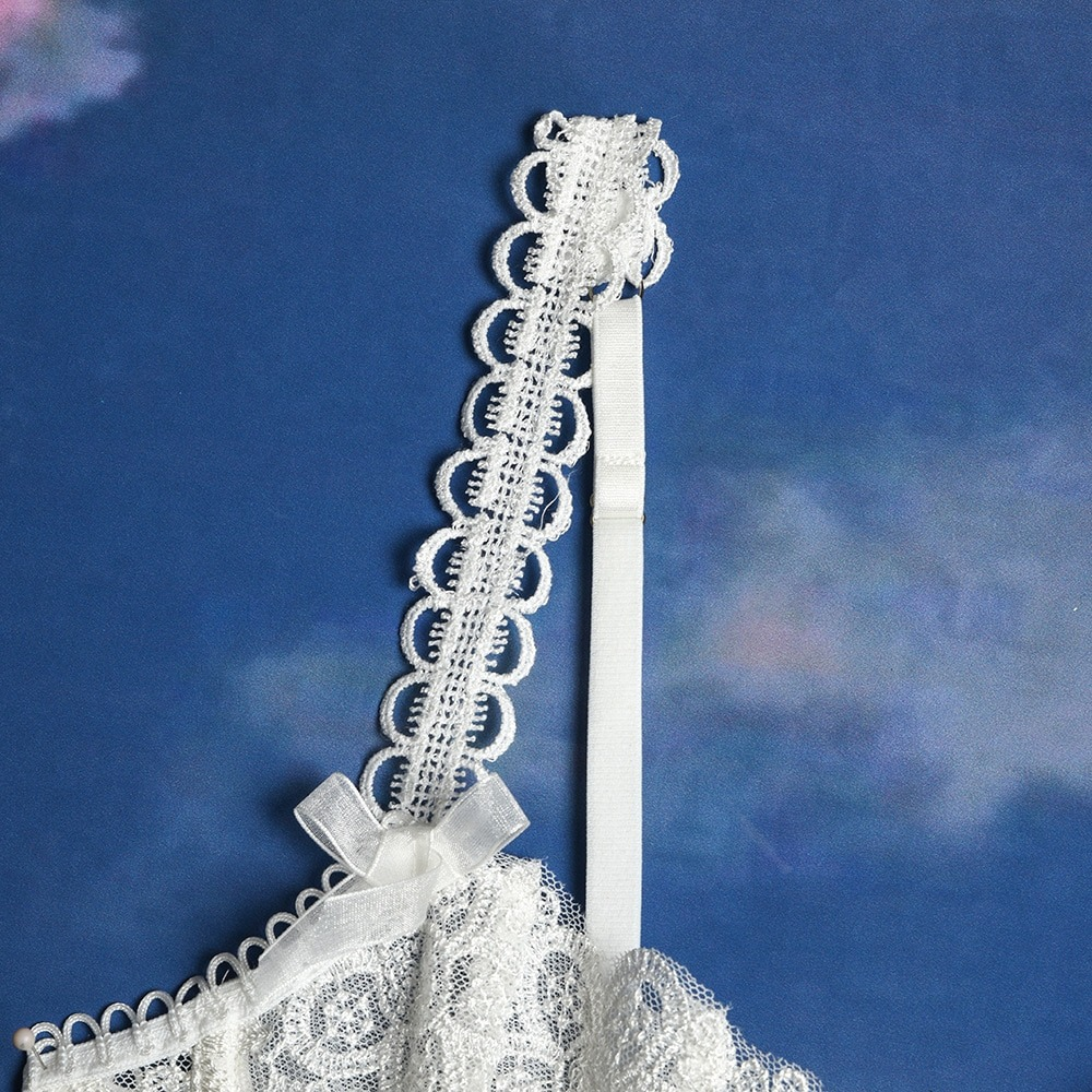 Close-up of a delicate white lace strap with scalloped edges and a bow detail, perfect for feminine lingerie.