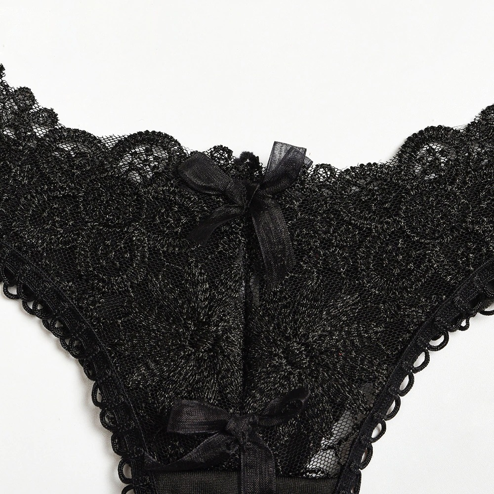 Close-up of women's black lace panties with intricate floral pattern and satin bows, perfect for a gothic lingerie set.