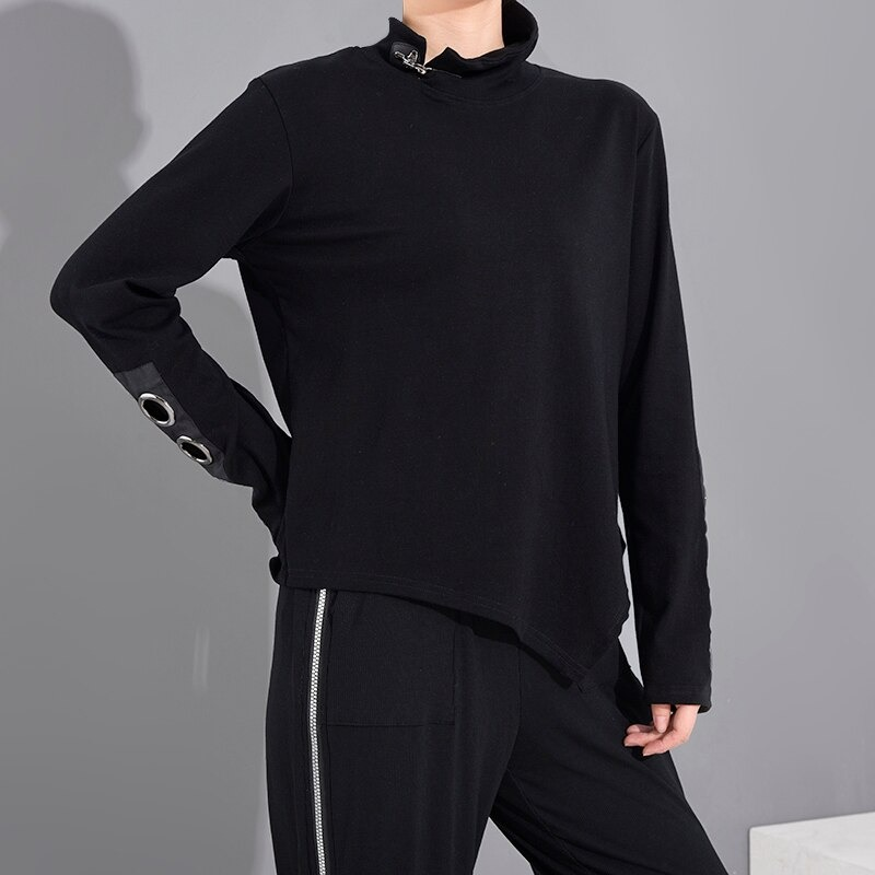 Women's long sleeve black asymmetrical top with stand collar and hollow out sleeves featuring metallic rings.