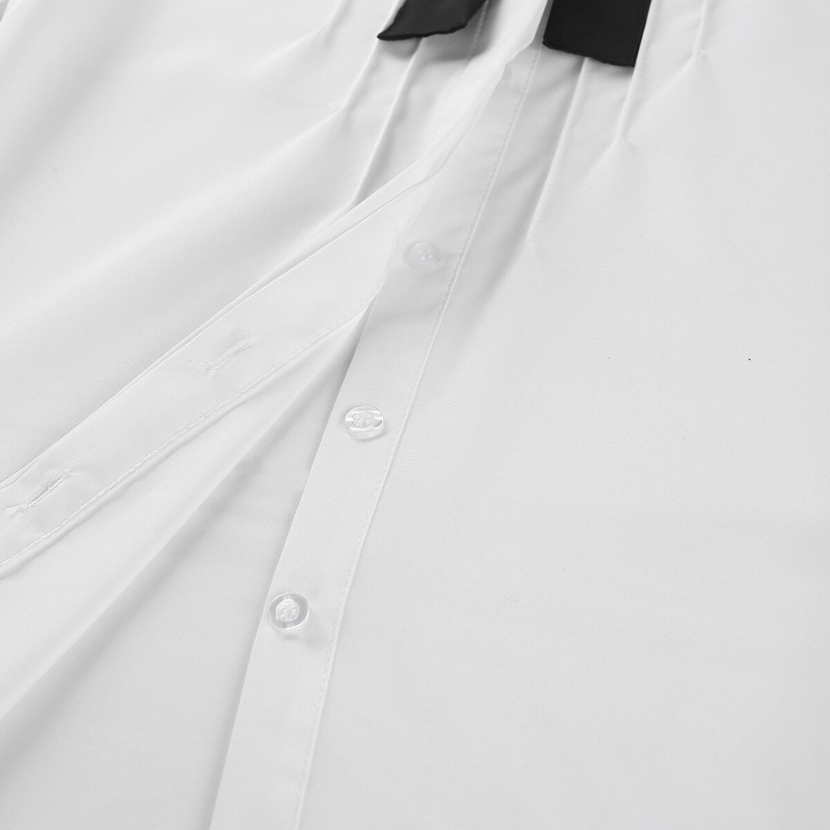 Close-up of a white long sleeve button-up shirt with a black removable bowknot and turn-down collar.
