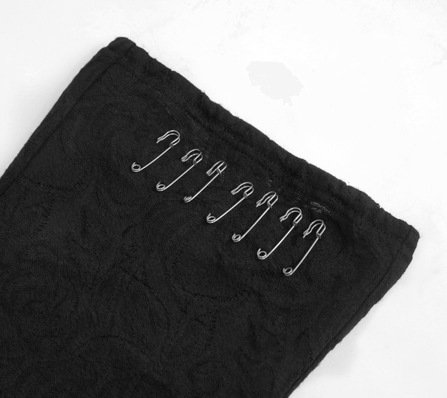 Close-up of black fabric with silver safety pins for gothic style women's top, showcasing trendy design details.