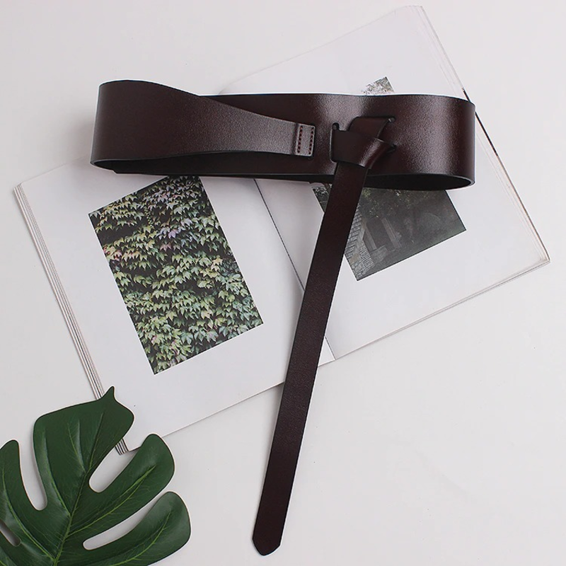 Stylish women's luxury designer belt on an open book, showcasing soft wide long PU leather in dark brown.