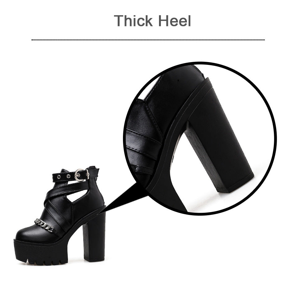 Close-up of women's black platform ankle boots showcasing thick heel and chain detail for gothic style.