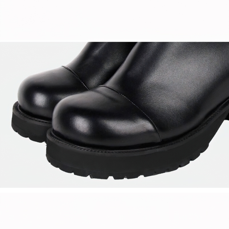 Close-up of women's black PU leather boots featuring shiny rounded toes and sturdy tractor soles for a stylish punk look.
