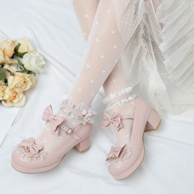 Cute pink round toe Mary Jane sandals with bows, paired with heart-patterned tights and a flowy dress.