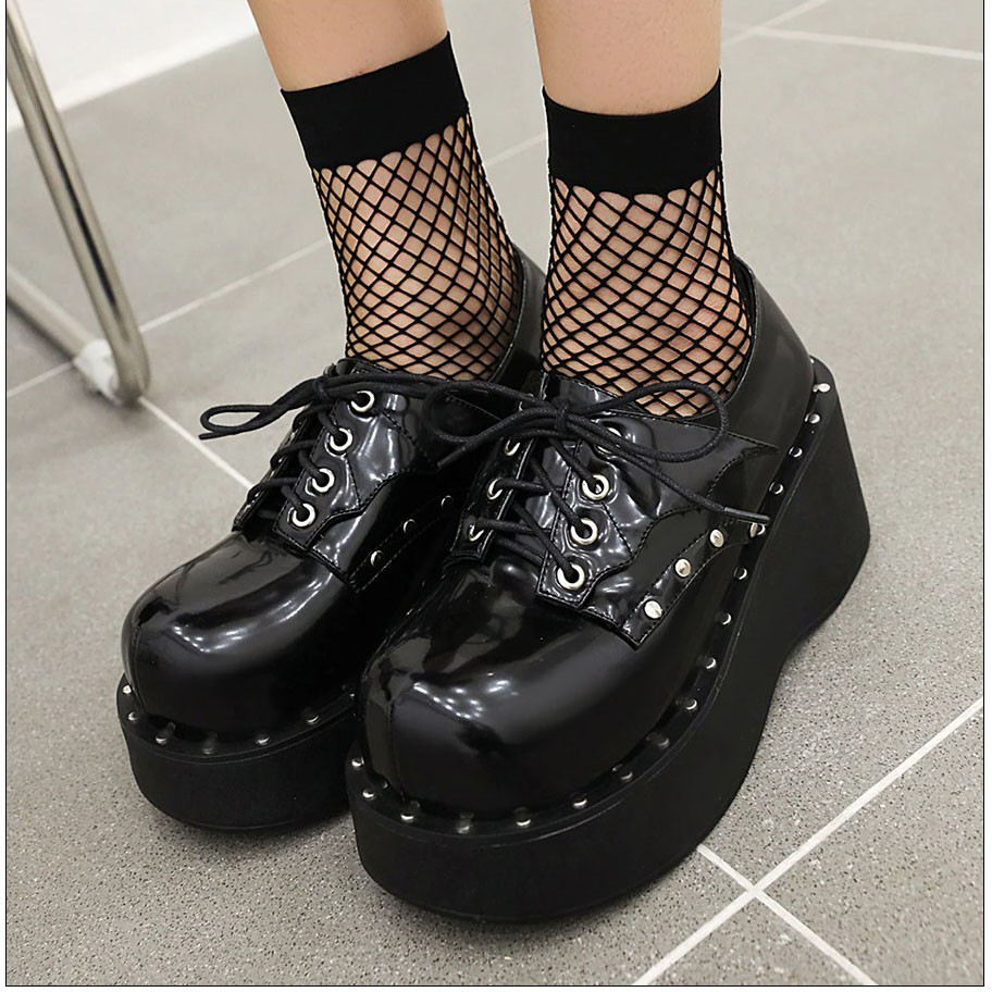 Stylish women's punk platform shoes in glossy black with lace-up design and fishnet socks.