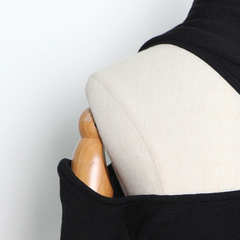 Close-up of a black women's slim top with one off-shoulder detail on a mannequin for alternative fashion styling.