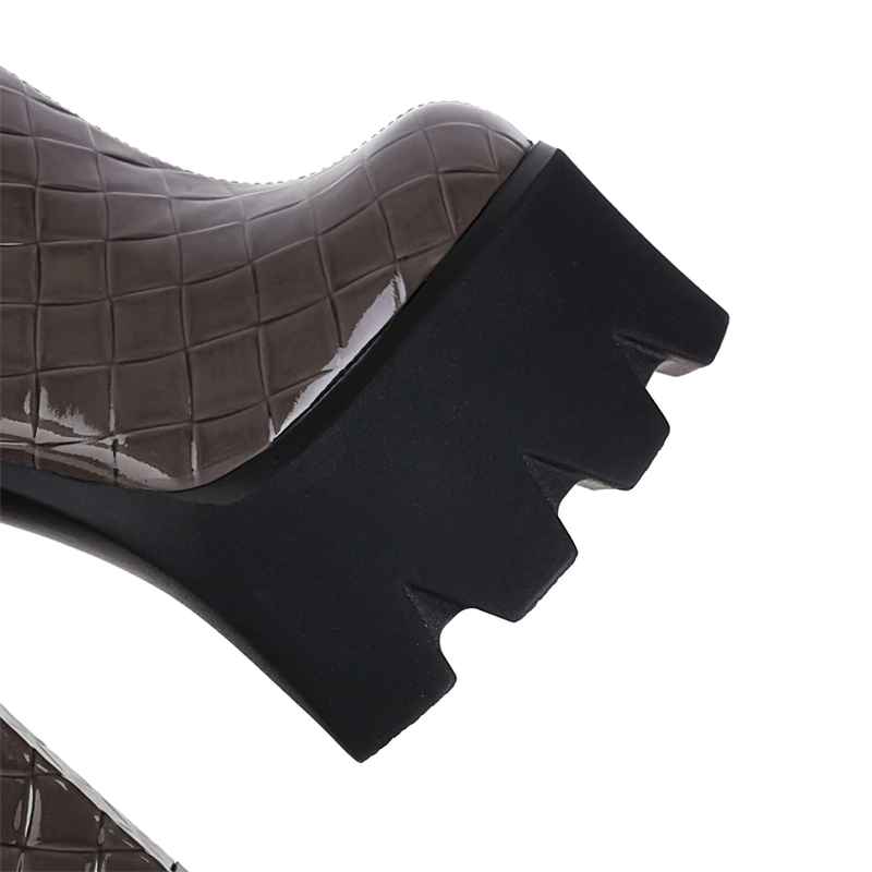 Close-up of patent leather high heel platform boot in brown with a chunky black heel and quilted texture.