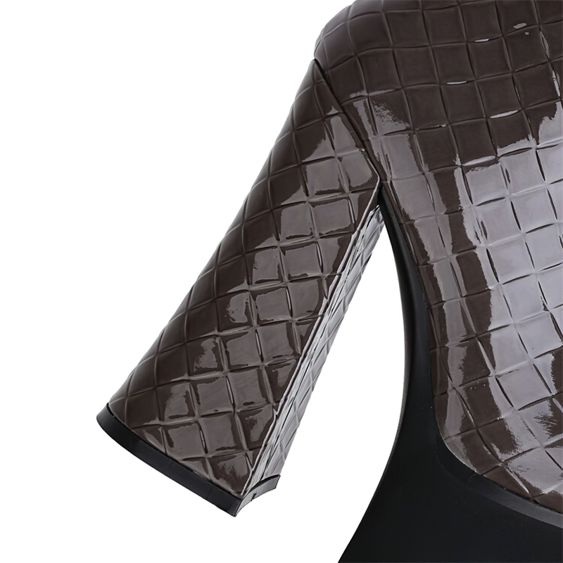 Close-up of women's high heel platform boot in shiny patent leather with quilted texture and chunky heel.