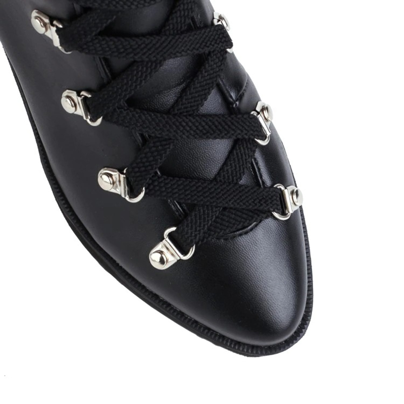 Close-up of women's gothic black platform boots featuring lace-up design and silver rivets for a punk style.