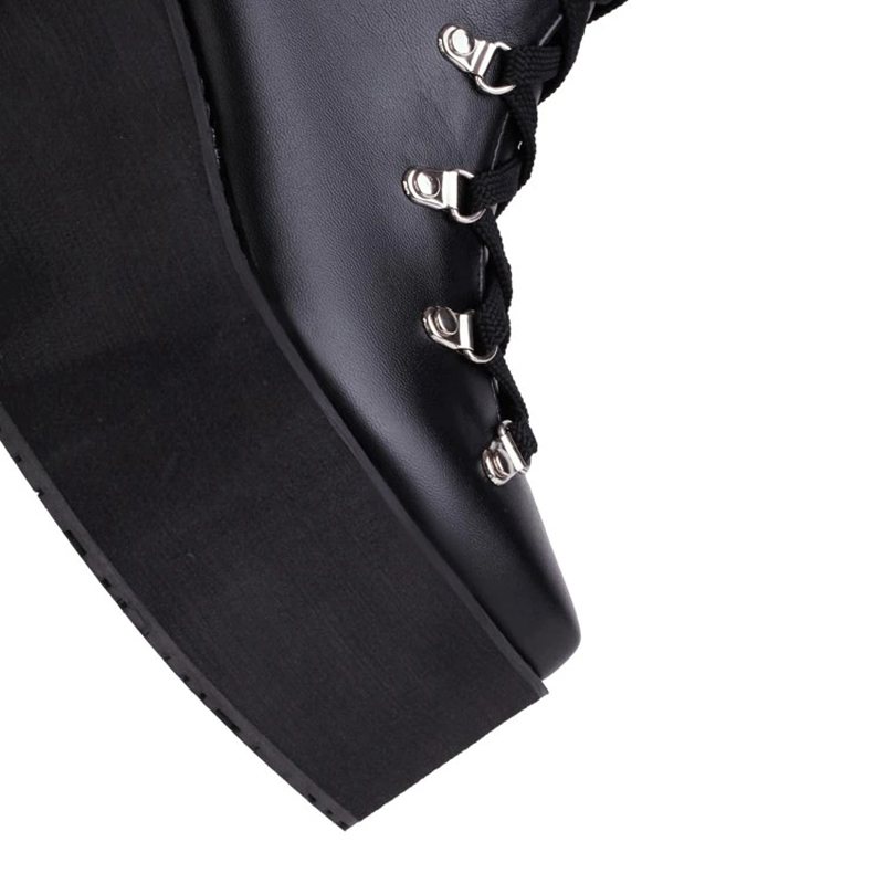 Close-up of women's super high black platform boots with lace-up detail and silver rivets in punk style.