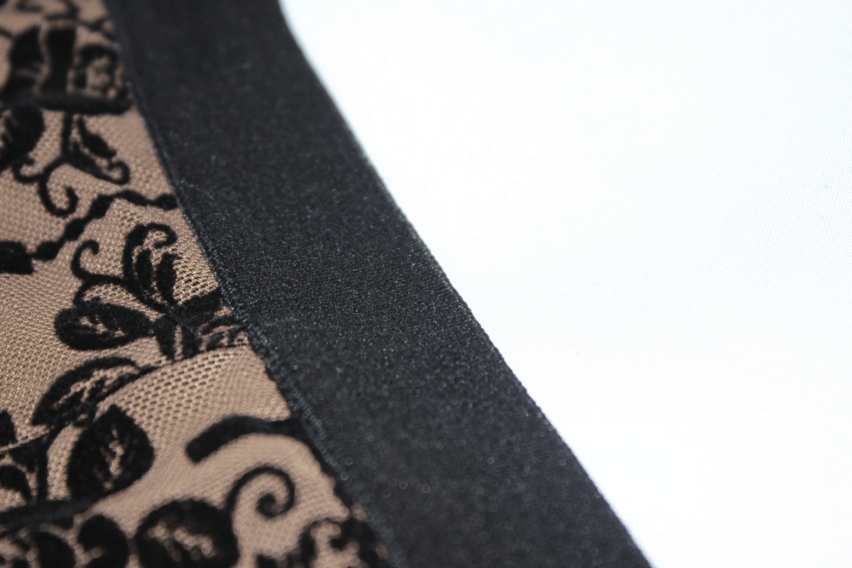 Close-up of elegant black lace design on apricot transparent mesh leggings with smooth waistband.