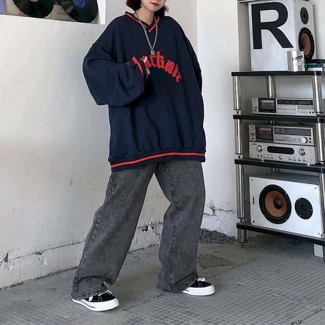 Trendy women's oversized v-neck baseball sweatshirt in navy, paired with relaxed jeans for a casual look.