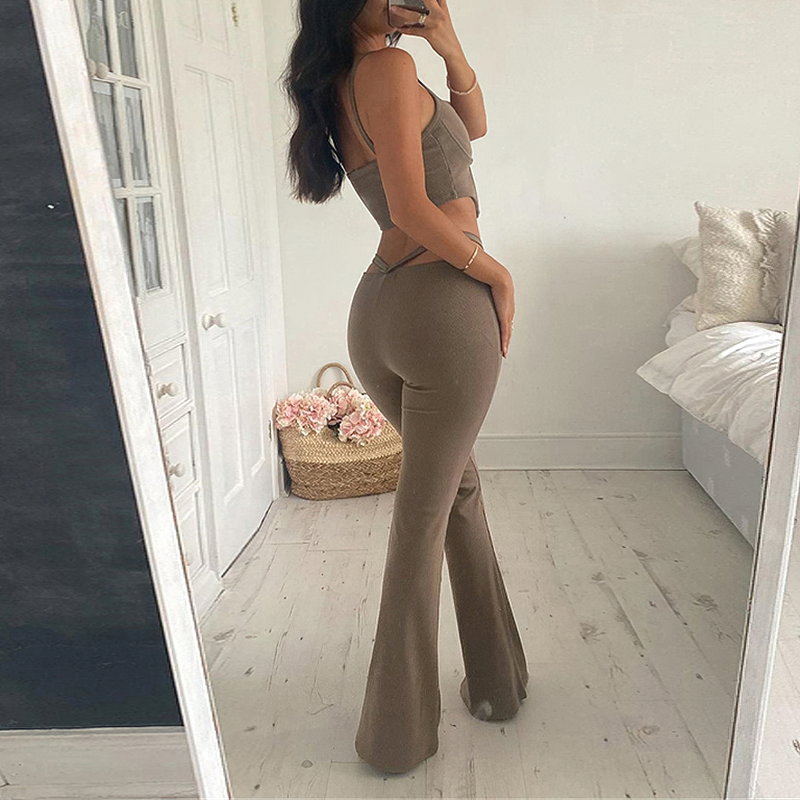 Woman in fitted brown bell bottom pants, showcasing a stylish gothic look in a cozy room.