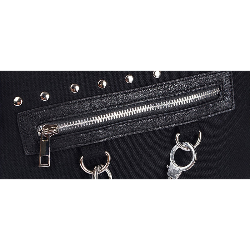 Close-up of vintage women's black tote bag showing rivets, zippers, and gothic metal details.
