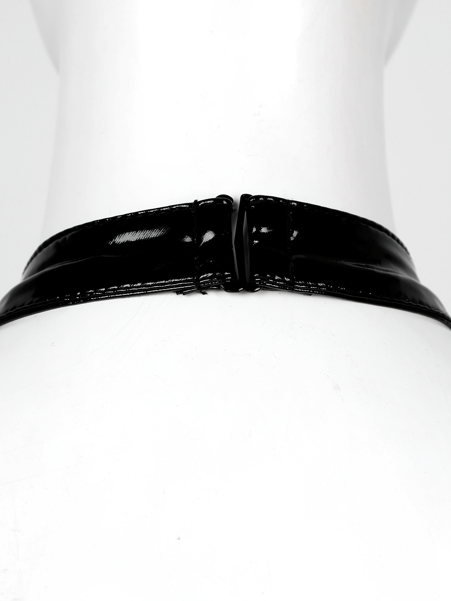 Close-up of the back view of a black patent leather strap from a sexy women's bodysuit.