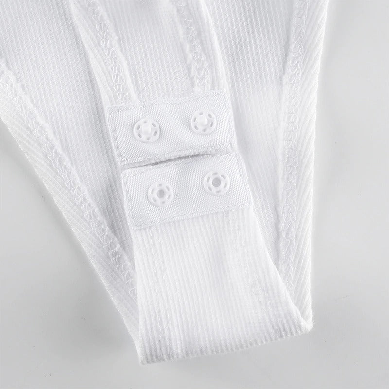 Close-up of white bodysuit straps featuring button fastenings, showcasing a stylish and secure design for women's swimwear.